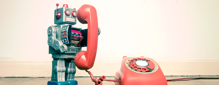 metal toy robot using a rotary telephone in front of a blank wall