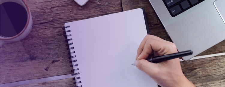 hand holding pen about to write on empty notebook sheet